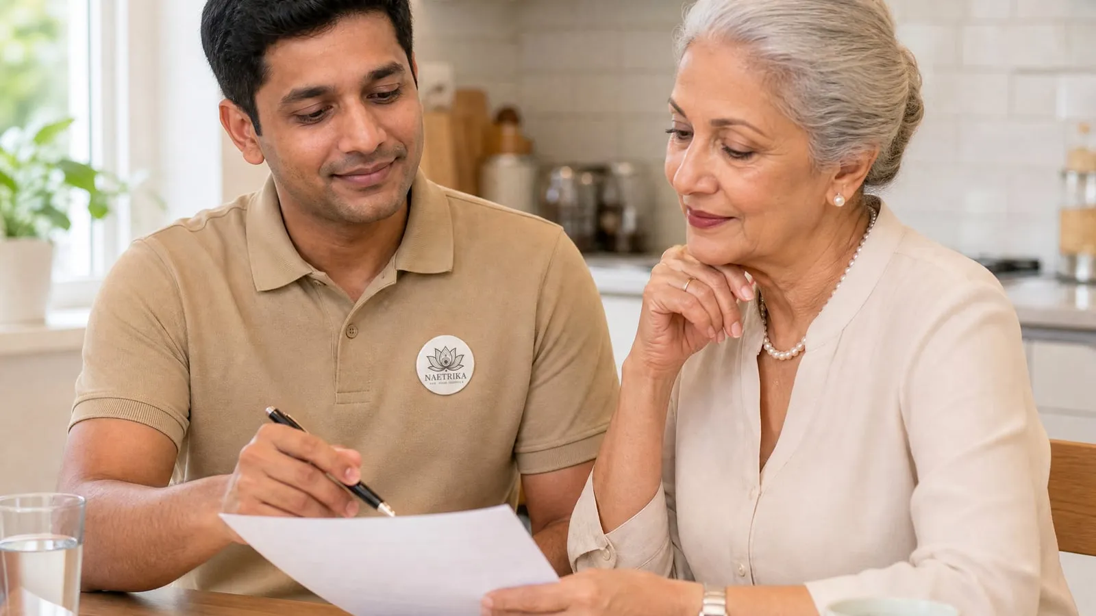A Naetrika caregiver reviewing a care agreement with an elderly woman at home